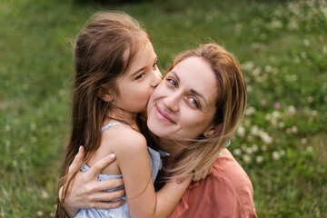 Obraz premium Daughter kissing and embrace her mom. Hapiness emotion. Family values. Happy family lifestyle. Happiness and joy of mom hugging her child.