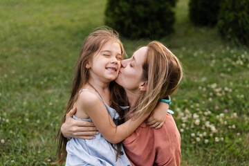 Obraz premium Daughter kissing and hug her mom. Hapiness emotion. Family values. Happy family lifestyle. Happiness and joy of mom hugging her child.
