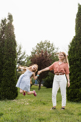 Naklejka na ściany i meble Mom and daughter having fun together. Happy family lifestyle. Daughter jumping, smiling and laughing. Love in family.