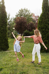 Naklejka na ściany i meble Mom and daughter having fun together. Happy family lifestyle. Daughter jumping, smiling and laughing. Love in family.
