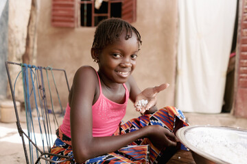 Pretty little African child with a smile showing a handful of cooked white rice to the camera; Rice...