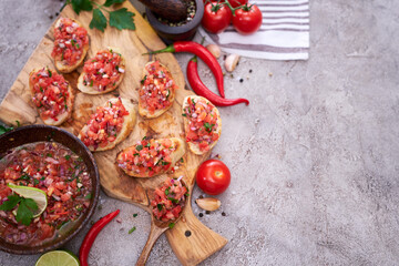 tasty salsa bruschetta snacks at domestic kitchen on wooden cutting board