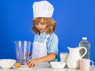 Portrait of chef child in cook hat. Cooking at home, kid boy preparing food from vegetable and fruits. Healthy eating.