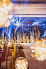 Flower arrangement for summer wedding, made of roses and green branches on a dinner table in the restaurant. , glass and plates in the restaurant outside on a windy day with film grain effect