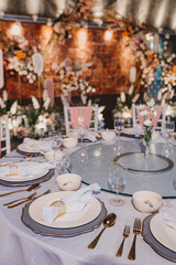 Flower arrangement for summer wedding, made of roses and green branches on a dinner table in the restaurant. , glass and plates in the restaurant outside on a windy day with film grain effect