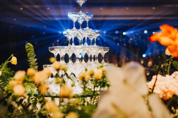 Flower arrangement for summer wedding, made of roses and green branches on a dinner table in the restaurant. , glass and plates in the restaurant outside on a windy day with film grain effect