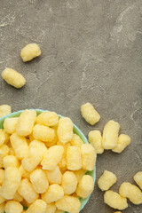 Sweet corn sticks in bowl on grey background. Vertical photo.