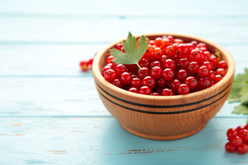 Bowl with ripe red currant on blue wooden background. Top view.