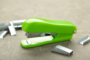 Green stapler on grey background. Top view