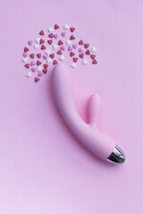 Pink vibrator toy for adults lies on a pink background, next to decorative hearts mimic an orgasm. Conceptual photo. - obrazy, fototapety, plakaty