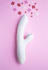 White vibrator toy for adults lies on a pink background, next to decorative hearts mimic an orgasm. Conceptual photo. - 512930263