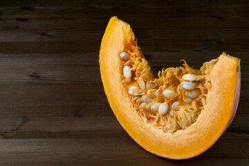 Fresh organic pumpkin slice on dark wooden background