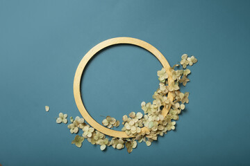 Golden ring and dried hydrangea flowers on a turquoise background. Flat lay, top view, copy space.