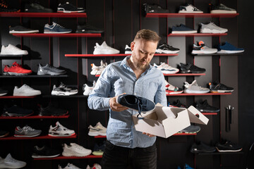 Young man choosing sneakers at sports shop, shoe shopper