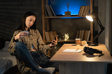 Asian girl holding credit card and using phone at home at night. Online shopping, E-commerce, Internet banking, spending money