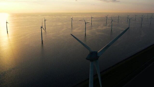 Working offshore wind farm, sunset view. Aerial view of wind turbines in Windpark, Netherlands. Concept: power plant, climate change, sustainable resources, green energy.