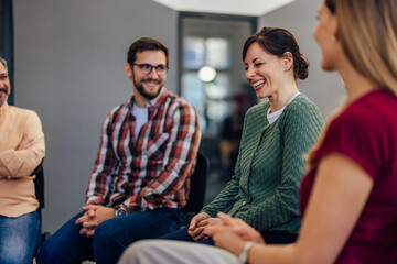 Photo of a smiling man and woman attending the group therapy, laughing together.