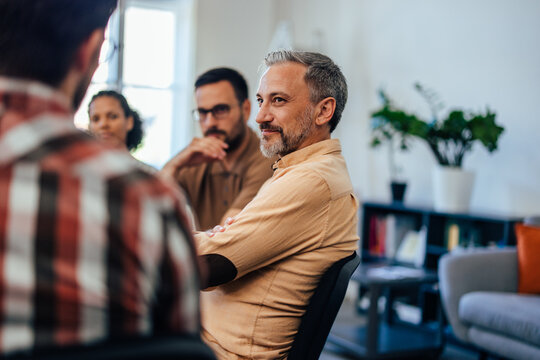 A mature man sitting and listening to another man from the group.