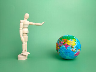 Wooden mannequin and earth globe on a green background