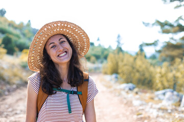 Portrait of a woman with a backpack and a straw hat