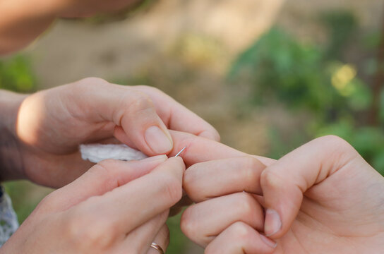 A splinter in a child's hand. The woman is trying to pull the splinter out of the child's hand