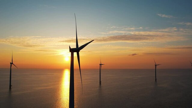 Aerial view of wind turbines, wind mills at sunset. Working offshore wind farm. Concept: power plant, climate change, sustainable resources, global warming, alternative energy source, renewable energy