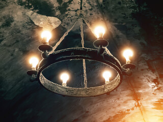Antique circular chandelier in a dark basement or cellar.