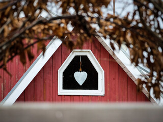 white heart in a window at a red wooden house