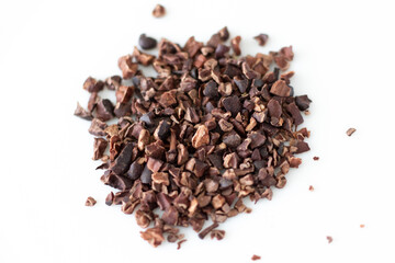 Crushed cacao beans in a pile on a white background. cacao nibs. Selective focus.