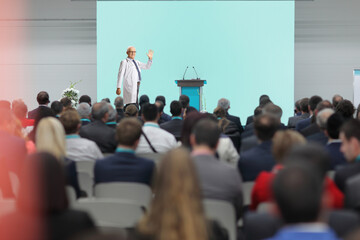 Male doctor waving at audience from the stage at a medical conference