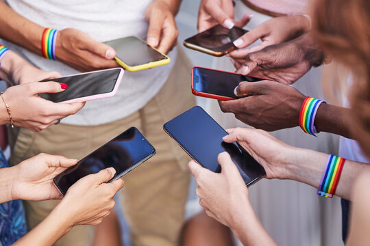 Group of multiracial people with LGBT rainbow flag wristbands using their mobile phones. Diversity, LGBT, unity and technology concept.
