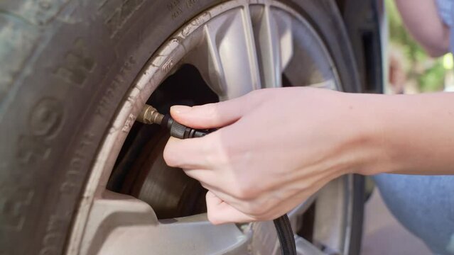 a woman inflates a flat car wheel on her own. tire service