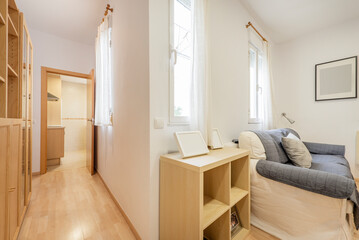 Fototapeta na wymiar Living room with several windows, light fabric sofa bed and hallway with oak furniture