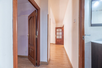 Distributor corridor of a house with light oak flooring and reddish wood carpentry on the doors