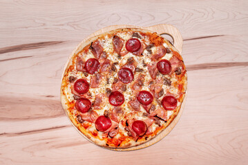 Delicious carnivorous pizza with ham, seasoned minced meat, pepperoni slices and mozzarella cheese with tomato and oregano