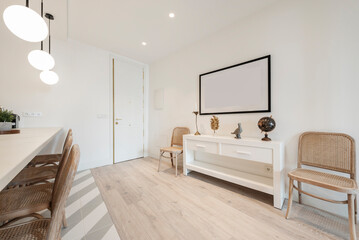 Hallway of a house with a white wooden sideboard, natural varnished wooden chairs and white lamps