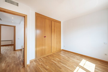 Empty bedroom with large fitted wardrobes with oak doors, matching oak floors and ducted air conditioning