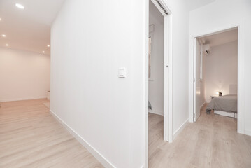 Empty house with corridors with light oak floors, doors to other rooms and white painted walls