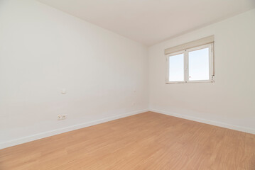 Empty room with light oak flooring, white carpentry on the baseboards and aluminum window with views