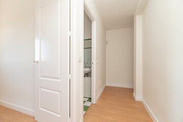 hallway of a house with light oak flooring with access doors to different rooms and white wood carpentry