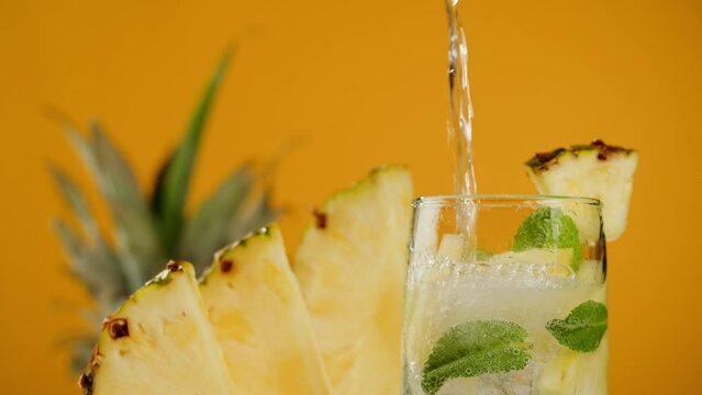 Pineapple lemonade on orange background. Fruit ananas cocktail close-up texture, healthy sweet drink. Detox drinking, summer refreshment concept.