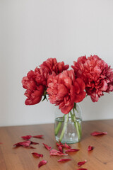 red peonies in a vase on the wooden  table