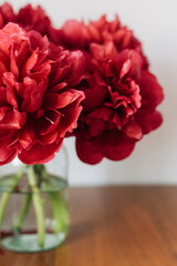 red peonies in a vase on the wooden  table
