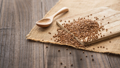 buckwheat grains scattered on a burlap cloth on a wooden table.