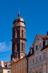 Fototapeta na wymiar St. Jacob protestant Church bell tower built with red sandstone in the historic centre of Göttingen Niedersachsen Germany. Facades of city houses in the main street “Weender Straße“ on summer day.