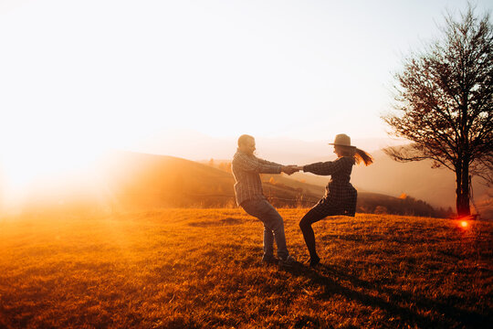 Beautiful couple circling holding hands enjoying each other at sunset. Holidays in the mountains.