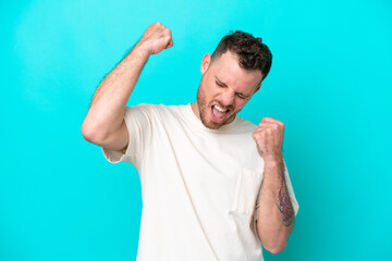 Young Brazilian man isolated on blue background celebrating a victory