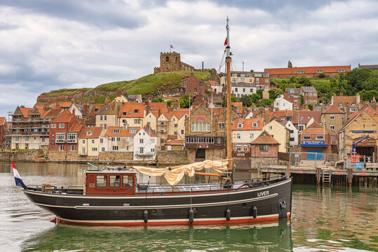 Masted boat enters a harbour.