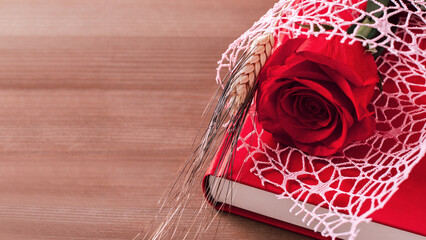 Red rose and red book on pink background, Sant Jordi holiday card