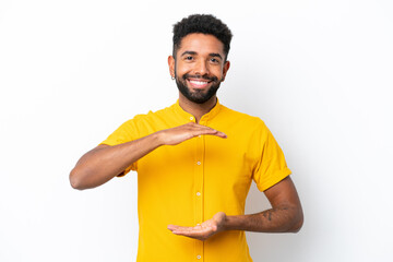 Young Brazilian man isolated on white background holding copyspace imaginary on the palm to insert an ad